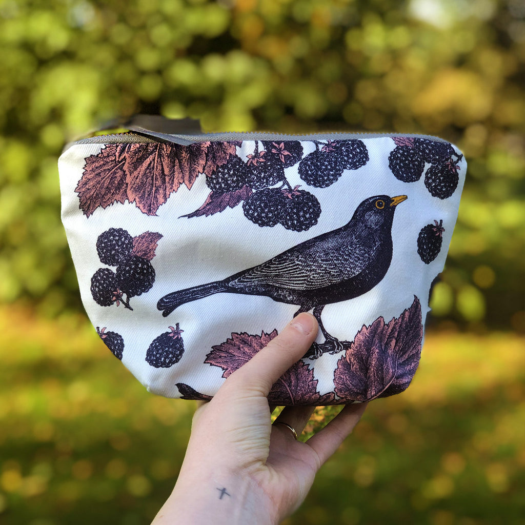 Hand printed with a gorgeous blackbird and bramble design, store all your best bits in this gorgeous cosmetic bag in rich purples and deep inky blues from Thornback & Peel - perfect for all of your treasures whether for day or night! White cosmetic bag hand printed with purple blackbirds and brambles with pink leaf detail.