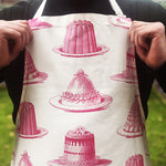 Load image into Gallery viewer, Be the star baker with our gorgeous hand printed 100% cotton aprons! In a mouth watering raspberry pink Jelly &amp; Cake design, this apron conjures up the feeling of kitchens of the past - crafting those perfect creations not just at seasonal celebrations, but all year round! Get practicing in this high quality Thornback &amp; Peel treat!
